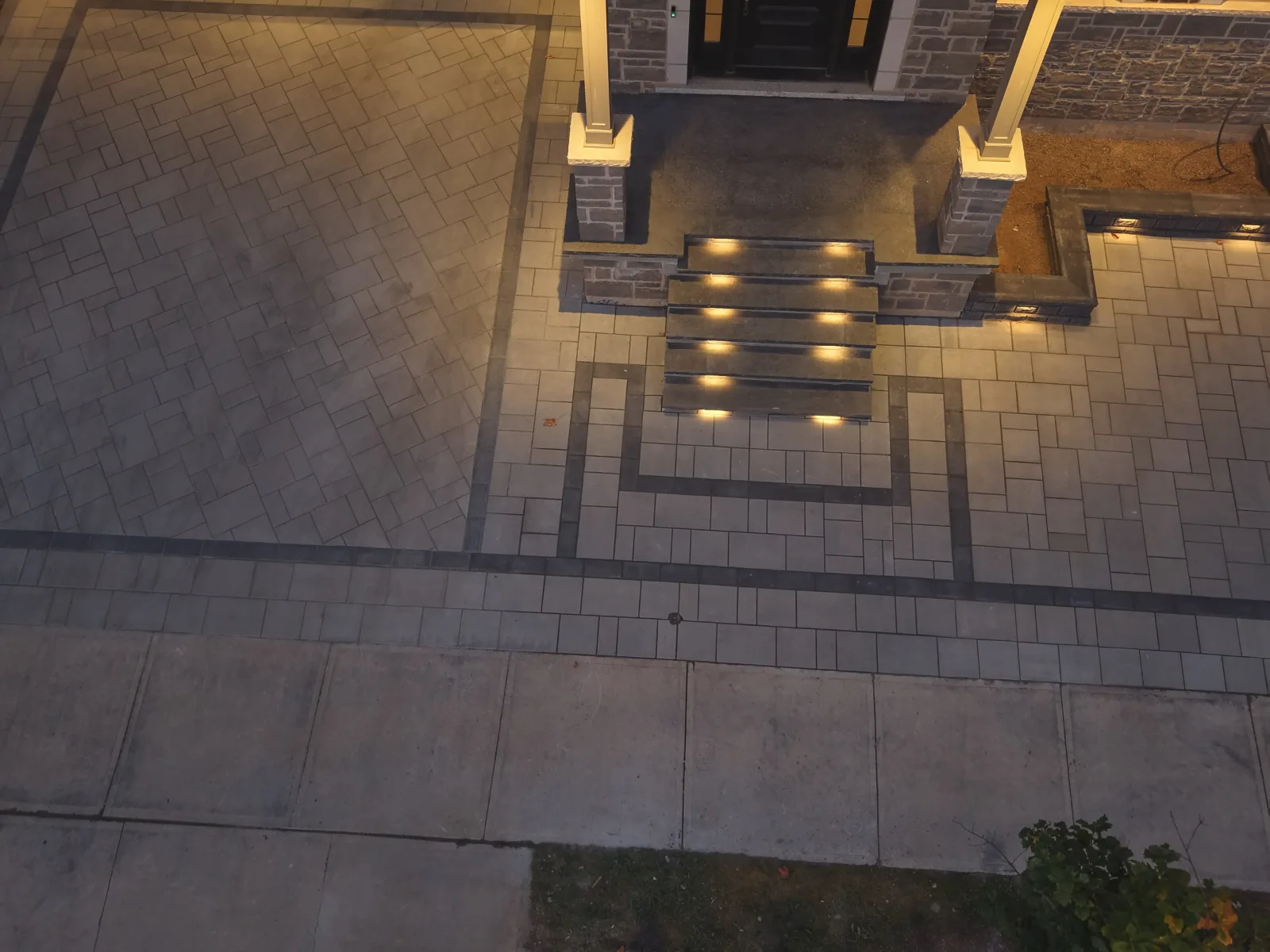 Illuminated stone steps framed by coordinated interlocking pavers